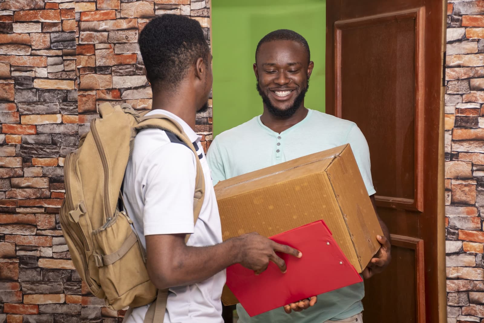 Smiling man at his front door receiving a delivery from a courier